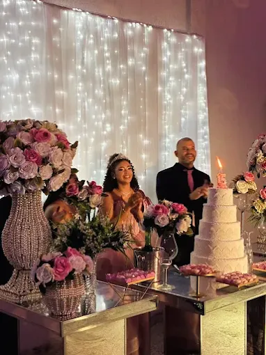 Casal celebra ao lado de bolo e flores em recepção